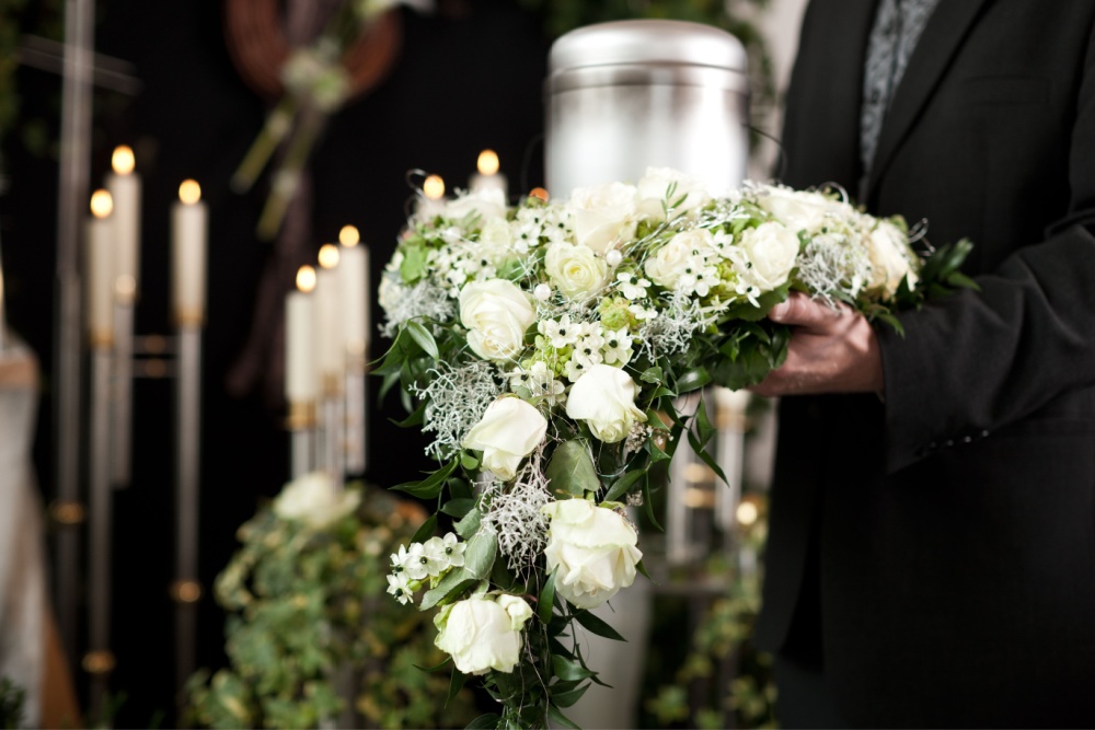 A man holding funeral flowers.